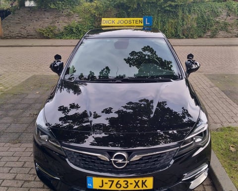 Onze zwarte Opel Astra-lesauto met het gele daklicht van Dick Joosten