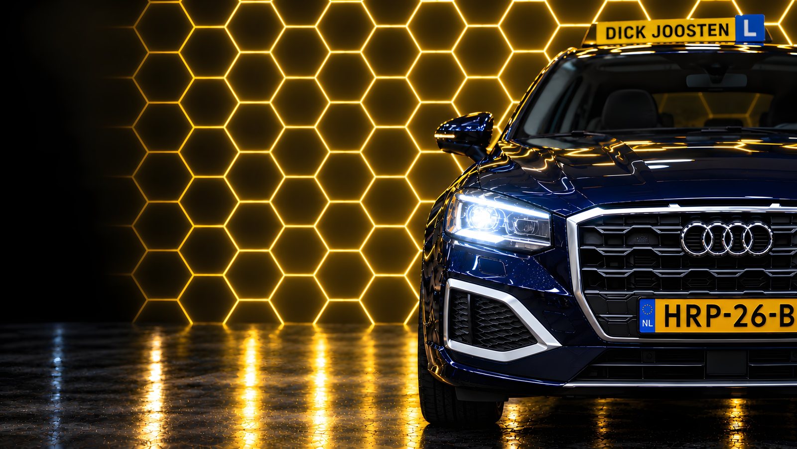 De blauwe Audi Q2-lesauto van Rijschool Dick Joosten met het daklicht, voor een wand van gele lichtende zeshoeken