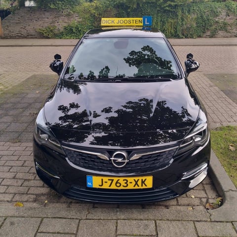 Onze zwarte Opel Astra-lesauto met het gele daklicht