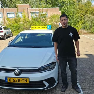 Daimyo naast de witte VW Polo-lesauto na zijn examen