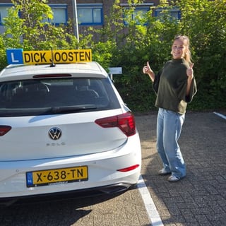 Senna naast de witte VW Polo-lesauto na haar examen