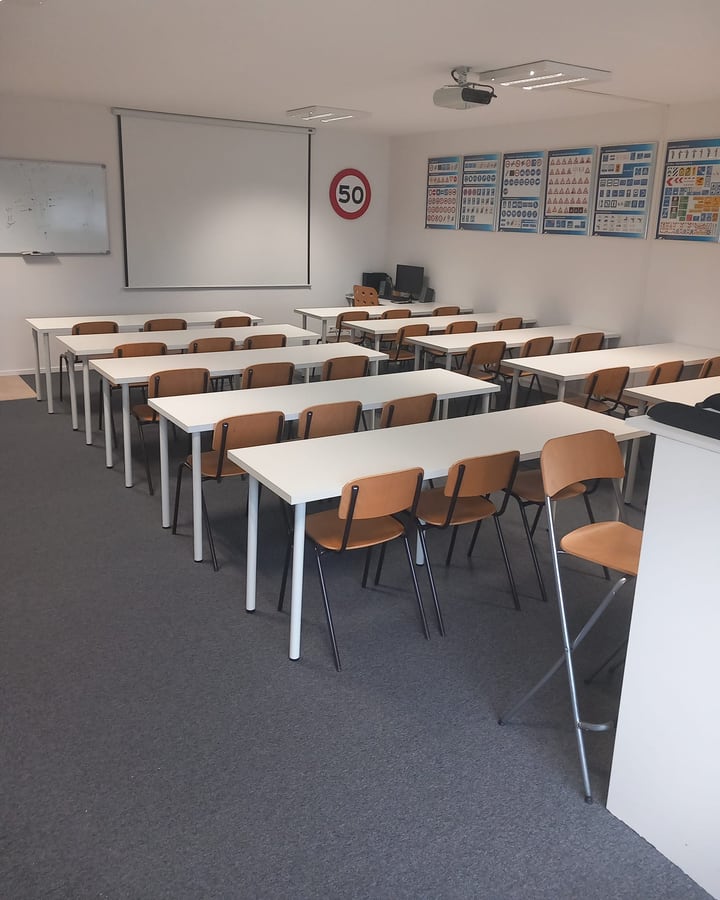 Ons theorielokaal in Arnhem-Zuid met tafels, scherm en verkeersborden aan de wand