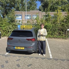Luke bij de lesauto na zijn examen