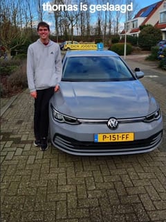 Thomas bij de VW Golf-lesauto na zijn examen