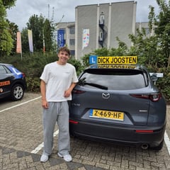 Jens naast de Mazda-lesauto na zijn geslaagde examen